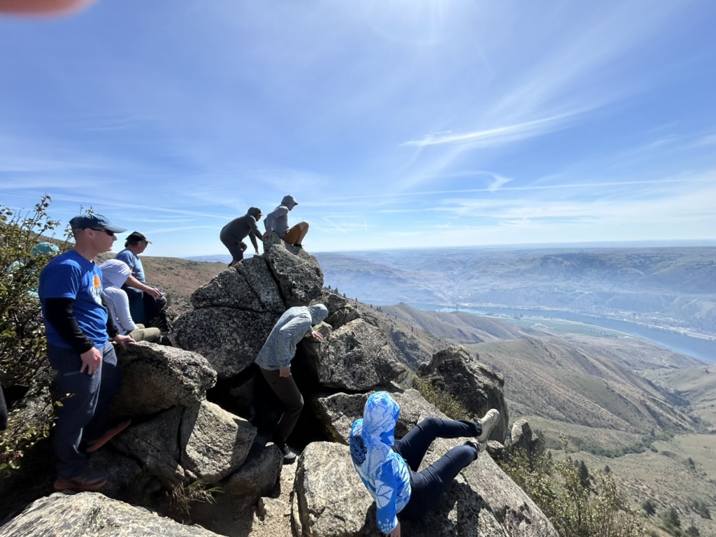 Spectators climbing rocks, overlooking a deep valley at Chelan.
